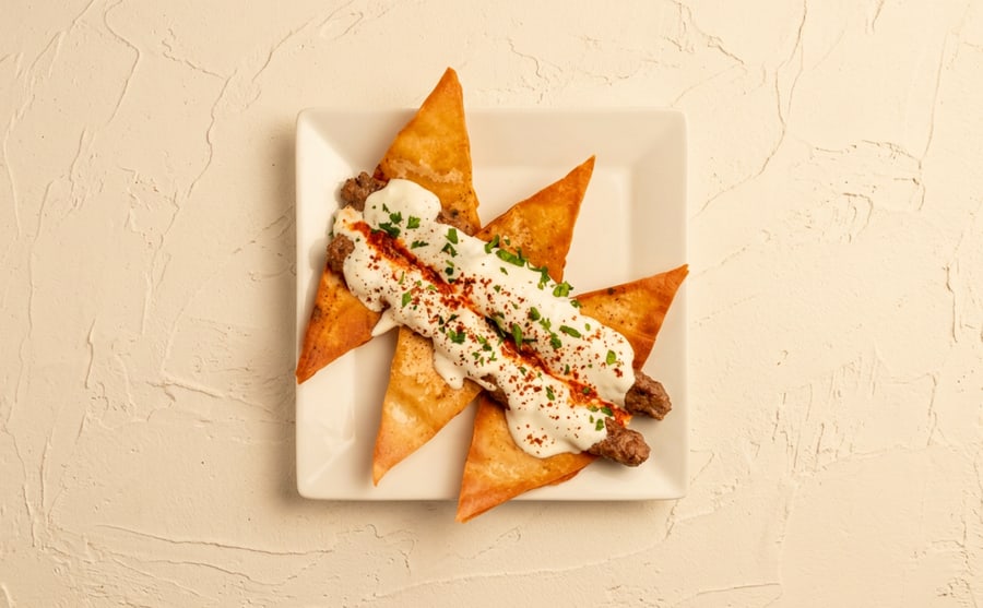 Yogurt kebab at Derian, Yerevan — Grilled minced-meat kebab laid over yogurt — the sharp cool underneath changes the whole plate, and that is the idea.